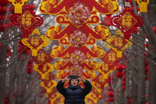 A woman takes a picture of red lanterns and decorations on display along the trees ahead of the Chinese Lunar New Year at Ditan Park in Beijing, Feb. 4, 2024. In many Asian cultures, the Lunar New Year is a celebration marking the arrival of spring and the start of a new year on the lunisolar calendar. It's the most important holiday in China where it's observed as the Spring Festival. (AP Photo/Andy Wong, file)