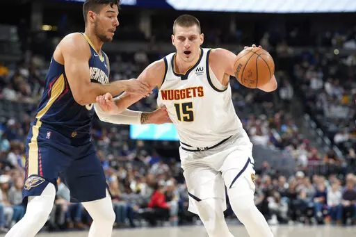 Denver Nuggets center Nikola Jokic, right, drives the lane to the rim as New Orleans Pelicans center Willy Hernangomez defends in the first half of an NBA basketball game Sunday, March 6, 2022, in Denver. (AP Photo/David Zalubowski)