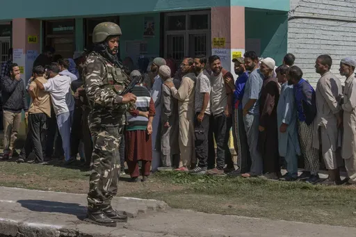 An Indian paramilitary soldier stands guard as people queue up at a polling booth to cast their vote in Bellow, south of Srinagar, Indian controlled Kashmir, Wednesday, Sept. 18, 2024. (AP Photo/Dar Yasin)