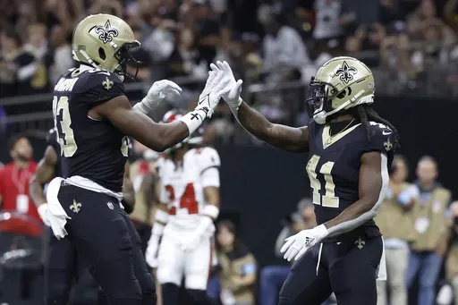 New Orleans Saints running back Alvin Kamara, right, is congratulated by tight end Juwan Johnson after scoring against the Tampa Bay Buccaneers during the first half of an NFL football game in New Orleans, Sunday, Oct. 13, 2024. (AP Photo/Butch Dill)