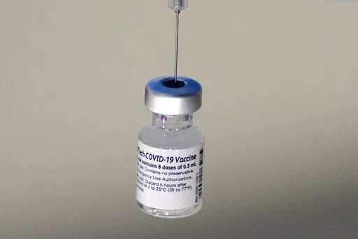 A syringe is placed into a vial of Pfizer-BioNTech vaccination at a COVID-19 clinic in Augusta, Maine, on Tuesday, Dec. 21, 2021. On Thursday, Oct. 20, 2022, Pfizer said it will charge $110 to $130 for a dose of its COVID-19 vaccine once the U.S. government stops buying the shots, but the drugmaker says it expects many people will continue receiving doses for free. (AP Photo/Robert F. Bukaty, File)