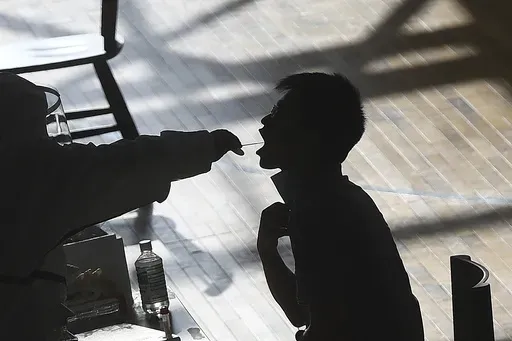 A medical worker takes a swab sample from a worker of the China Star Optoelectronics Technology (CSOT) company during a round of COVID-19 tests in Wuhan in central China's Hubei province, Aug. 5, 2021. (Chinatopix via AP, File)