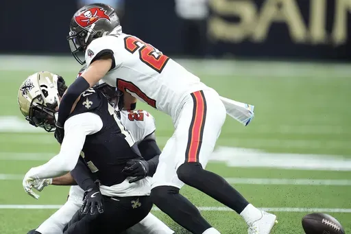 New Orleans Saints wide receiver Chris Olave, left, fumbles the ball while hit by Tampa Bay Buccaneers cornerback Zyon McCollum, top, and safety Tykee Smith, rear, that Antoine Winfield Jr. returned for a touchdown, during the first half of an NFL football game in New Orleans, Sunday, Oct. 13, 2024. (AP Photo/Michael Conroy)