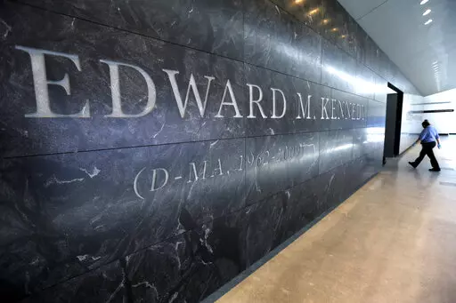 A passer-by walks near the engraved name of the late U.S. Sen. Edward M. Kennedy near the main entrance to the Edward M. Kennedy Institute, in Boston, March 23, 2015. An Associated Press review finds state and local governments have spent nearly $1 billion worth of federal coronavirus aid on projects that have little to do with combating the pandemic. Lawmakers delivered $5 million to pay off debts of the Edward M. Kennedy Institute for the U.S. Senate, a nonprofit established to honor the senat