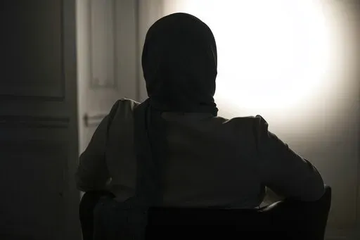 The sister, who refused to show and identify, of a woman imprisoned in Turkey is silhouetted during an interview with The Associated Press in Paris, Wednesday, Feb. 16, 2022. Shatz and a team of European lawyers filed a case against Greece at the European Court of Human Rights on behalf of a 32-year-old French woman who accuses the Hellenic country of forcibly pushing her back across the border from Greece to Turkey, where she claims she is a victim of political persecution. The woman, who is al