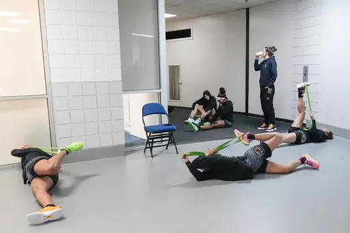 UCLA players stretch in the hallway of the MVP Arena before practice during the NCAA Tournament in Albany, N.Y., Saturday, March 30, 2024. The second year of the super regional format for the women's NCAA Tournament presented some logistical challenges for arena staff and the teams involved. The locker rooms were reserved for teams with practices and games. Those coming in for shootarounds came dressed and occasionally stretched in corridors while waiting for the court to become available.(AP Ph
