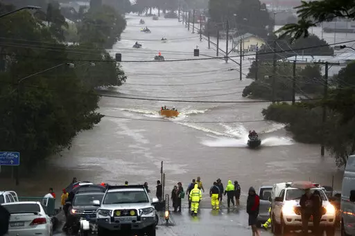 People use small boats to travel through flood water in Lismore, Australia, Monday, Feb. 28, 2022. Heavy rain is bringing record flooding to some east coast areas and claimed seven lives while the flooding in Brisbane, a population of 2.6 million, and its surrounds is the worst since 2011 when the city was inundated by what was described as a once-in-a-century event. (Jason O'Brien/AAP Image via AP)