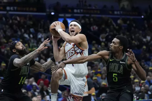 Phoenix Suns guard Devin Booker (1) goes to the basket between New Orleans Pelicans forward Brandon Ingram (14) and forward Herbert Jones (5) in the second half of an NBA basketball game in New Orleans, Friday, Jan. 19, 2024. The Suns won 123-109. (AP Photo/Gerald Herbert)