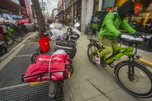 A food delivery worker rides down a sidewalk after a pickup from a restaurant in New York on Jan. 29, 2024. DoorDash is stepping up efforts to stop delivery drivers who are breaking traffic laws. (AP Photo/Bebeto Matthews, FILE)