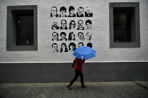 A woman shelters from the rain under an umbrella, while walking past a wall painted with portraits of prisoners of the Basque separatist armed group ETA, in the small village of Hernani, northern Spain, May 2, 2018. The United States is poised to remove five extremist groups, all believed to be defunct, from its list of foreign terrorist organizations. Several of these groups once posed significant threats, killing hundreds if not thousands of people across Asia, Europe and the Middle East. The 