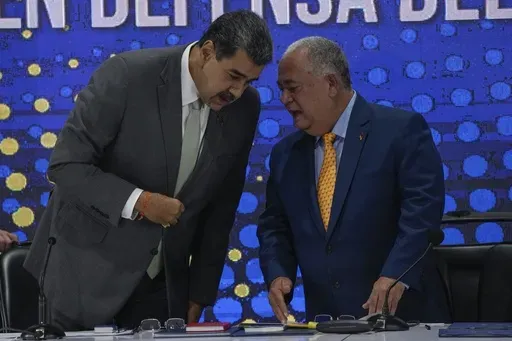 Venezuela's President Nicolas Maduro, left, speaks with National Electoral Council President Elvis Hidrobo Amoroso during the notification ceremony for the referendum about the future of a disputed territory with Guyana, in Caracas, Venezuela, Monday, Dec. 4, 2023. (AP Photo/Ariana Cubillos)
