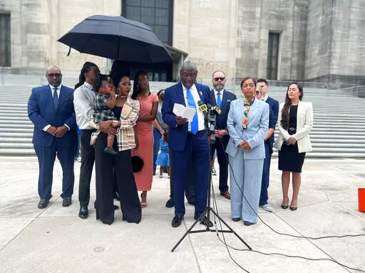 Nancy Davis, a Louisiana woman who was denied an abortion despite her fetus having a rare and fatal condition, stands on the steps of the state Capitol holding her one-year-old daughter, Friday, Aug. 26, 2022, in Baton Rouge, La. Davis, alongside her Attorney Ben Crump, abortion proponents and family, addressed the media on Friday. (AP Photo/Stephen Smith)