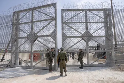 Israeli soldiers gather near a gate to walk through an inspection area for trucks carrying humanitarian aid supplies bound for the Gaza Strip, on the Israeli side of the Erez crossing into northern Gaza, on May 1, 2024. (AP Photo/Ohad Zwigenberg, File)