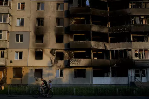 A man rides a bicycle in front of a building destroyed by attacks in Borodyanka, on the outskirts of Kyiv, Ukraine, Sunday, June 12, 2022. (AP Photo/Natacha Pisarenko)