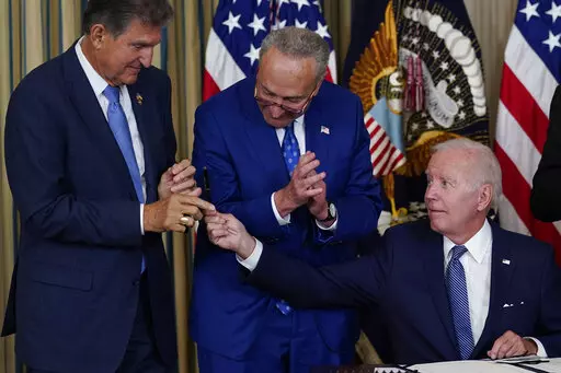 President Joe Biden hands the pen he used to sign the Democrats' landmark climate change and health care bill to Sen. Joe Manchin, D-W.Va., as Senate Majority Leader Chuck Schumer of N.Y., watches in the State Dining Room of the White House in Washington, Aug. 16, 2022. Manchin made a deal with Democratic leaders as part of his vote pushing the party's highest legislative priority across the finish line last month. Now, he's ready to collect. But many environmental advocacy groups and lawmakers 