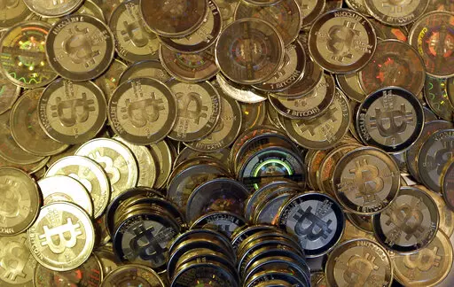This April 3, 2013, file photo shows bitcoin tokens in Sandy, Utah. The Cuban government said Thursday, August 26, 2021, that it will start recognizing cryptocurrencies like Bitcoin as payment. With investors eager to get in early on new cryptocurrency projects, some unscrupulous developers have attracted investments, then walked away before building what they promised — leaving their supporters with worthless holdings. The rug pull, which gets its name from the expression “pulling the rug o