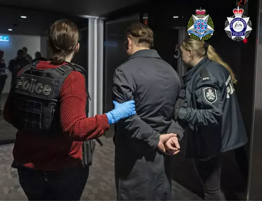 In this photo provided by the Australian Federal Police a man is taken into custody in Melbourne, Wednesday, June 14, 2023. A drug syndicate that tried to smuggle tons of methamphetamine from Canada to Australia and New Zealand by hiding it in shipments of maple syrup and canola oil has been busted, authorities said Thursday, June 15. (Australian Federal Police via AP)