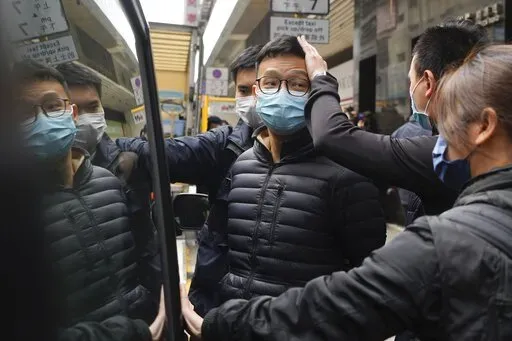 Editor of Stand News Patrick Lam, center, is escorted by police officers into a van after they searched evidence at his office in Hong Kong, Wednesday, Dec. 29, 2021. Hong Kong police raided the office of the online news outlet on Wednesday after arresting several people for conspiracy to publish a seditious publication. (AP Photo/Vincent Yu)