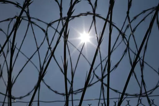 The sun shines through concertina wire on a fence at the Louisiana State Penitentiary in Angola, La., April 26, 2014. Louisiana's prison system routinely holds people beyond their legal release dates, the U.S. Department of Justice said Wednesday, Jan. 25, 2023, in a report concluding that the state has failed for years to develop solutions to “systemic overdetentions” that violate inmates' rights and are financially costly to taxpayers. (AP Photo/Gerald Herbert, File)