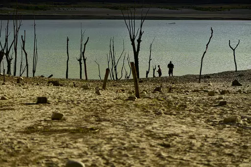 People walk close to the border at Yesa's reservoir affected by drought, on a sunny summer day in Yesa, around 55 kilometers (34,17 miles), from Pamplona, northern Spain, Sept. 14, 2022. Widespread drought that dried up large parts of Europe, the United States and China this past summer was made 20 times more likely by climate change, according to a new study. (AP Photo/Alvaro Barrientos)