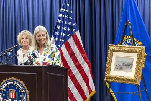 Francoise Parlagi, center, and Helen Lowe, far left, descendants of the original owners the Claude Monet painting entitled "Bord de Mer," smile as it is returned to them at the FBI New Orleans office on Wednesday, Oct. 9, 2024. (Chris Granger/The Times-Picayune/The New Orleans Advocate via AP)