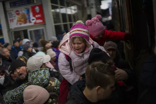 People holding their children struggle to get on a train to Lviv at the Kyiv station, Ukraine, Monday, March 7, 2022. Russia announced yet another cease-fire and a handful of humanitarian corridors to allow civilians to flee Ukraine. Previous such measures have fallen apart and Moscow's armed forces continued to pummel some Ukrainian cities with rockets Monday. (AP Photo/Emilio Morenatti)