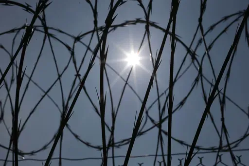 The sun shines through concertina wire on a fence at the Louisiana State Penitentiary in Angola, La., April 26, 2014. (AP Photo/Gerald Herbert, File)