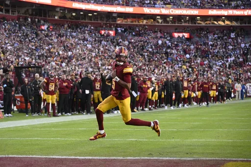Washington Commanders quarterback Jayden Daniels (5) scores on a 2-point conversion attempt during the second half of an NFL football game against the Dallas Cowboys, Sunday, Nov. 24, 2024, in Landover, Md. (AP Photo/Nick Wass)