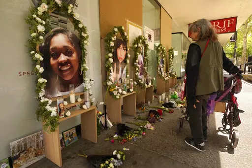 A passerby pauses at a memorial for the six people killed in mass shooting in Sacramento, Calif., on Wednesday, April 6, 2022. Multiple people were killed and injured in the shooting that occurred Sunday, April, 3, 2022. (AP Photo/Rich Pedroncelli)