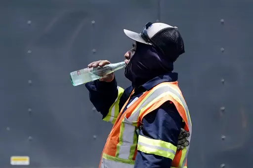 Standing in the mid-afternoon heat, a worker takes a break to drink during a parking lot asphalt resurfacing job in Richardson, Texas, June 20, 2023. While unrelenting heat set in across Texas this summer, opponents of a sweeping new law targeting local regulations took to the airwaves and internet with an alarming message: outdoor workers would be banned from taking water breaks. Workers would die, experts and advocates said, with high temperatures topping 100 degrees Fahrenheit (38 degrees Cel