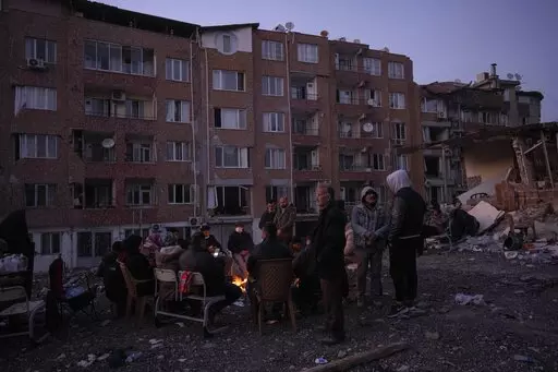 Friends and relatives of the Dagli family family gather around bonfires while rescue teams, search for family members under the rubble of a destroyed building in Antakya, southeastern Turkey, Wednesday, Feb. 15, 2023. Ever since the powerful 7.8 earthquake that has become Turkey's deadliest disaster in modern history, survivors have been gathering outside destroyed buildings, refusing to leave. (AP Photo/Bernat Armangue)