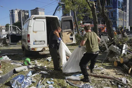 Municipal workers carry a dead body killed after an apartment building was hit by Russian air bomb killing at least three and injuring 23, in Kharkiv, Ukraine, Saturday, June 22, 2024. (AP Photo/Andrii Marienko)
