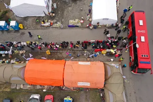 An aerial view of refugees queuing for transport at the border crossing at Medyka, Poland, Sunday March 13, 2022, where the main flow of Ukrainian refugees cross into Poland. The U.N. refugee agency says more than 2.5 million people, including more than a million children, have already fled Ukraine. It has become an unprecedented humanitarian crisis in Europe and the fastest refugee exodus since World War II. (AP Photo)