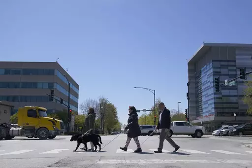 Maureen Reid, left, and her guide dog, Gaston, cross the intersection of Wood Street and Roosevelt Avenue with Sandy Murillo, center, and Geovanni Bahena, relying on an audible signal for the blind, on April 26, 2023, in Chicago. Faced with a growing backlash, the U.S. Census Bureau said Tuesday, Feb. 6, 2024, that it is pausing plans to change how it asks people about disability in its most comprehensive survey, a move that would have overhauled how disabilities are defined by the nation's larg