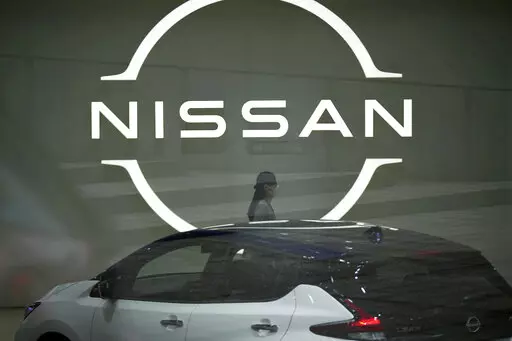 A staff walking near a Nissan logo at Nissan headquarters is seen though a window on May 12, 2022, in Yokohama near Tokyo. Nissan and Renault have changed their mutual cross-shareholdings to the same 15%, ironing out a source of conflict in the Japan-French auto alliance. (AP Photo/Eugene Hoshiko, File)