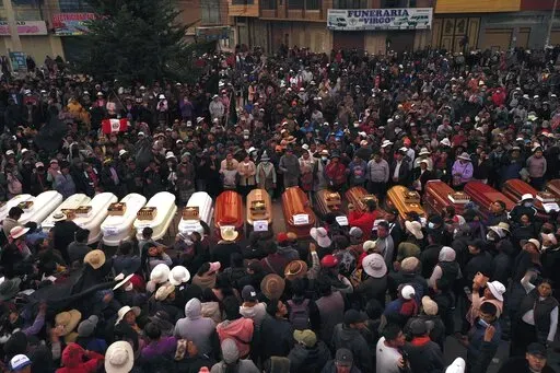 Residents surround coffins during a vigil for the more than a dozen people who died during the unrest in Juliaca, Peru, Tuesday, Jan. 10, 2023. At least 17 people died Monday in southeast Peru as protests seeking immediate elections resumed in neglected rural areas of the country still loyal to ousted President Pedro Castillo. (AP Photo/Jose Sotomayor)