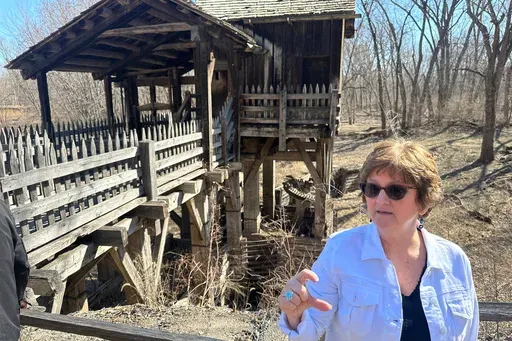 Gina Gillmore-Wolter, president of the New Salem Lincoln League, explains that the drive shaft, just over her right shoulder, has fallen out of the floor of the gristmill, part of the reconstructed village of New Salem where Abraham Lincoln lived from 1831 to 1837, March 10, 2025, in Petersburg, Ill. (AP Photo/John O'Connor)
