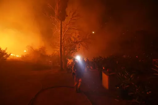 Fire crews prepare to defend a home as a wildfire advances Thursday, Dec. 7, 2017, in Bonsall, Calif. Environmental groups have been arguing in California courts that developers are not fully considering the risks of wildfire and choked evacuation routes when they plan housing developments near fire-prone areas. (AP Photo/Gregory Bull, File)