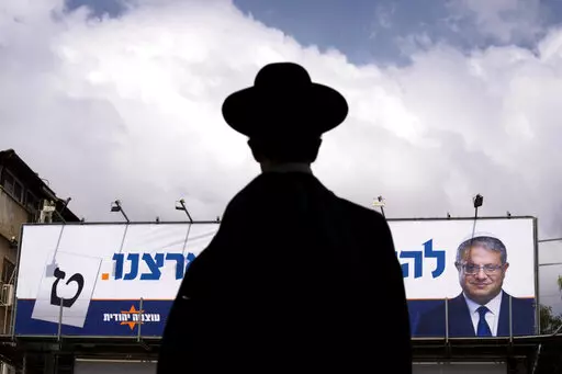 An ultra-Orthodox Jewish man walks by an election campaign billboard showing Itamar Ben-Gvir, Israeli far-right lawmaker and the head of "Jewish Power" party, in Bnei Brak, Israel Monday, Oct. 24, 2022. Israel is holding its fourth election in less than two years. Israel's most extremist politician, known for his inflammatory anti-Arab speeches and stunts, is attracting new supporters from a previously untapped demographic young ultra-Orthodox Jews, one of the fastest-growing segments of the cou