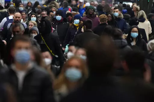 Shoppers walk down Oxford Street, Europe's busiest shopping street, in London, Dec. 23, 2021. The British government confirmed Saturday Feb. 19, 2022, that people with the coronavirus will not be legally required to self-isolate starting next week, as part of a plan for “living with COVID” that is also likely to see testing for the virus scaled back. (AP Photo/Frank Augstein, File)