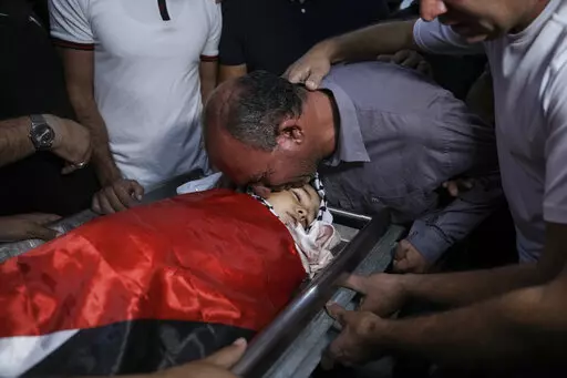 Father of 7-year-old Palestinian boy Rayan Suleiman, kisses his body at a hospital in the West Bank village of Beit Jala just before his funeral Friday, Sept. 30, 2022. The U.S. State Department has called on Israel to open a "thorough" investigation into the mysterious death of the boy, who collapsed and died shortly after Israeli soldiers came to his home in the occupied West Bank. Relatives said he had no previous health problems and accused the army of scaring the child to death. The army ca