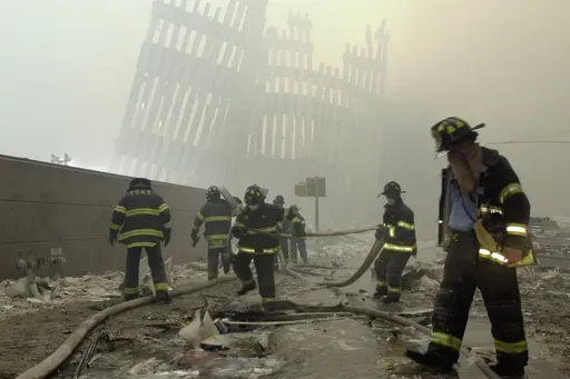 In this Sept. 11, 2001 photo, firefighters work beneath destroyed mullions, the vertical struts which once faced the outer walls of the World Trade Center towers, after a terrorist attack on the twin towers in New York. (AP Photo/Mark Lennihan, File)