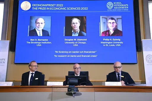 From left, Tore Ellingsen, Hans Ellegren and John Hassler members of the Royal Swedish Academy of Sciences announce the Sveriges Riksbank Prize in Economic Sciences in Memory of Alfred Nobel 2022, during a press conference at the Royal Swedish Academy of Sciences in Stockholm, Sweden, Monday, Oct. 10, 2022. From left on screen Ben S. Bernanke, Douglas W. Diamond and Philip H. Dybvig have been awarded 2022's Nobel Prize in economic sciences. (Anders Wiklund/TT News Agency via AP)