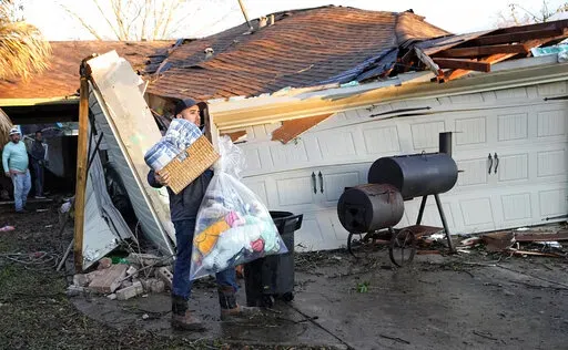 Mario Mendoza carries items out of a friend's storm-damaged home Tuesday, Jan. 24, 2023, in Pasadena, Texas. A powerful storm system took aim at Gulf Coast Tuesday, spawning tornados that caused damage east of Houston. (AP Photo/David J. Phillip)