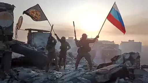 In this grab taken from video released by Prigozhin Press Service on Saturday, May 20, 2023, Yevgeny Prigozhin's Wagner Group military company members wave a Russian national and Wagner flag atop a damaged building in Bakhmut, Ukraine. The head of the Russian private army Wagner claims his forces have taken control of the city of Bakhmut after the longest and most grinding battle of the Russia-Ukraine war, but Ukrainian defense officials have denied it. In a video posted on Telegram, Prigozhin s