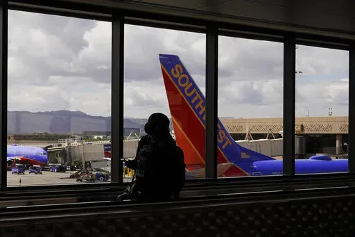 A passenger walks past a Southwest Airlines plane at Sky Harbor International Airport in Phoenix, March 26, 2021. AT&T and Verizon have agreed to delay the launch of a new slice of 5G service by two weeks after airlines and the nation's aviation regulator complained about potential interference with systems on board planes. (AP Photo/Sue Ogrocki, File)