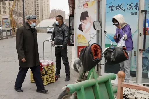 In this March 18, 2021, file photo, residents wearing masks walk along the streets of Aksu in western China's Xinjiang region. (AP Photo/Ng Han Guan, File)