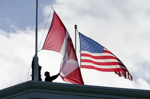 Washington State Park workers put up a new Canadian flag in front of an American flag about to be replaced during scheduled maintenance atop the Peace Arch in Peace Arch Historical State Park Monday, Nov. 8, 2021, in Blaine, Wash. (AP Photo/Elaine Thompson, File)