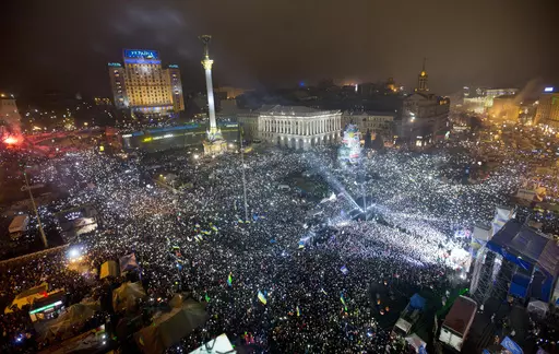 In this Jan. 1, 2014, file photo Pro-European Union activists hold lights as they sing the Ukrainian national anthem, celebrating the New Year in Kyiv's main square. At least 100,000 Ukrainians gathered in a sign of support for integration with Europe. On Nov. 21, 2023, Ukraine marks the 10th anniversary of the uprising that eventually led to the ouster of the country’s Moscow-friendly president. (AP Photo/Efrem Lukatsky, file)