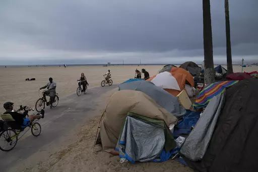 People ride their bikes past a homeless encampment set up along the boardwalk in the Venice neighborhood of Los Angeles on June 29, 2021. Democratic Mayor Karen Bass, who was elected in November 2023 after promising to take on the city’s out-of-control homeless crisis, announced Monday, April 17, she would recommend spending what she called a record $1.3 billion next year to get unhoused people into shelter and treatment programs. (AP Photo/Jae C. Hong, File)